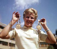 Doppel-Olympiasiegerin Ingrid 
		Kr&auml;mer aus der DDR - sie erk&auml;mpfte Siege im Kunstspringen und im Turmspringen bei den XVII. Olympischen
	 Spielen in Rom - pr&auml;sentiert im August 1960 im olympischen Dorf lachend ihre Medaillen. 